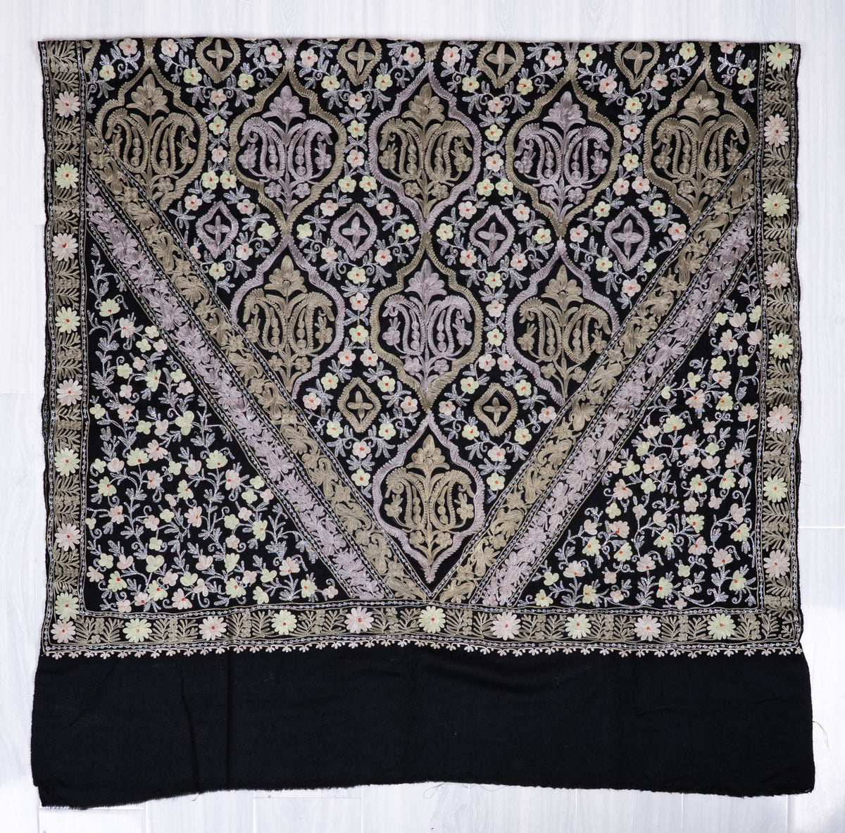 Black shawl spread flat, with pale Aari medallions in a V-shaped panel, floral side sections and a plain black end