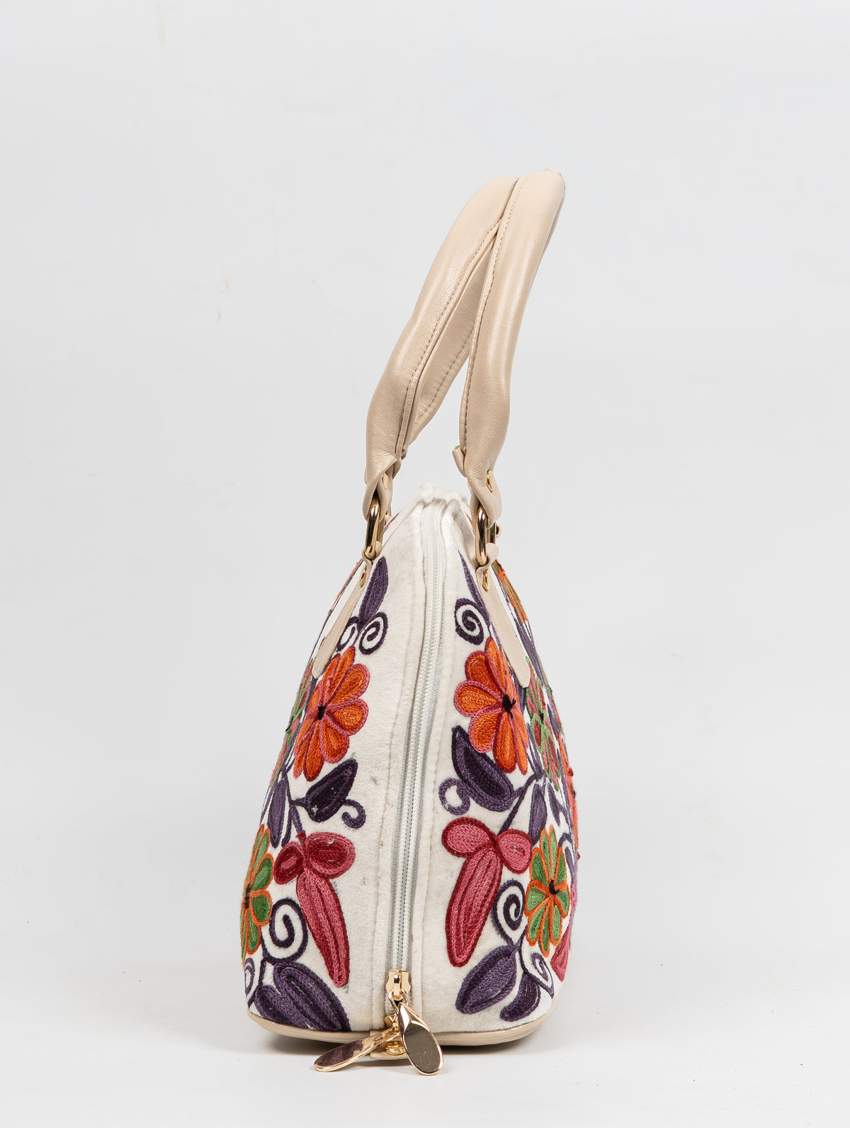 Side view of an ivory floral Aari tote showing the long zip, cream handles and gold-toned zip pulls