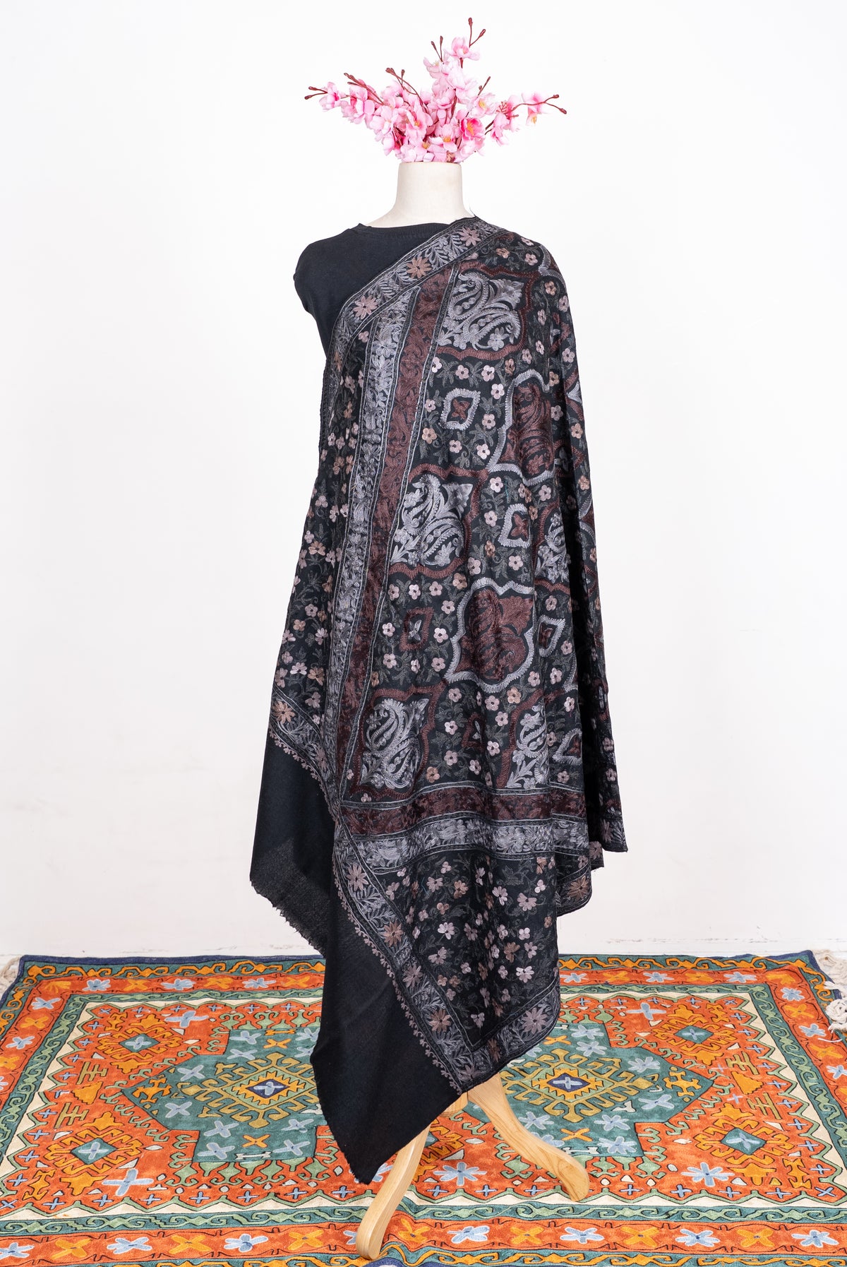 Full-length black shawl draped over one shoulder, showing silver and muted-rose paisley panels and floral borders