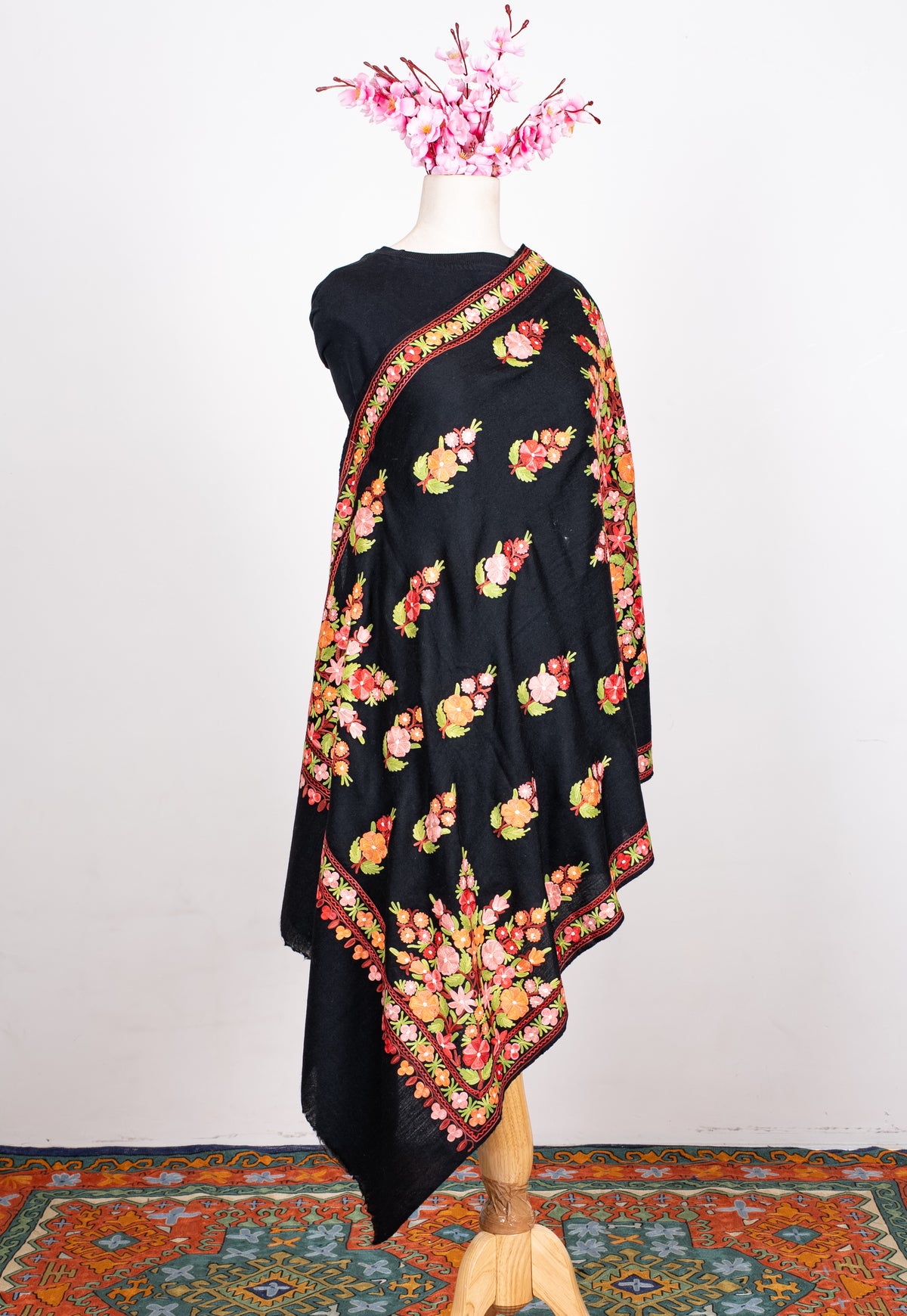 Full-length black shawl draped on a mannequin, with colourful bouquets, larger corner flowers and narrow floral borders
