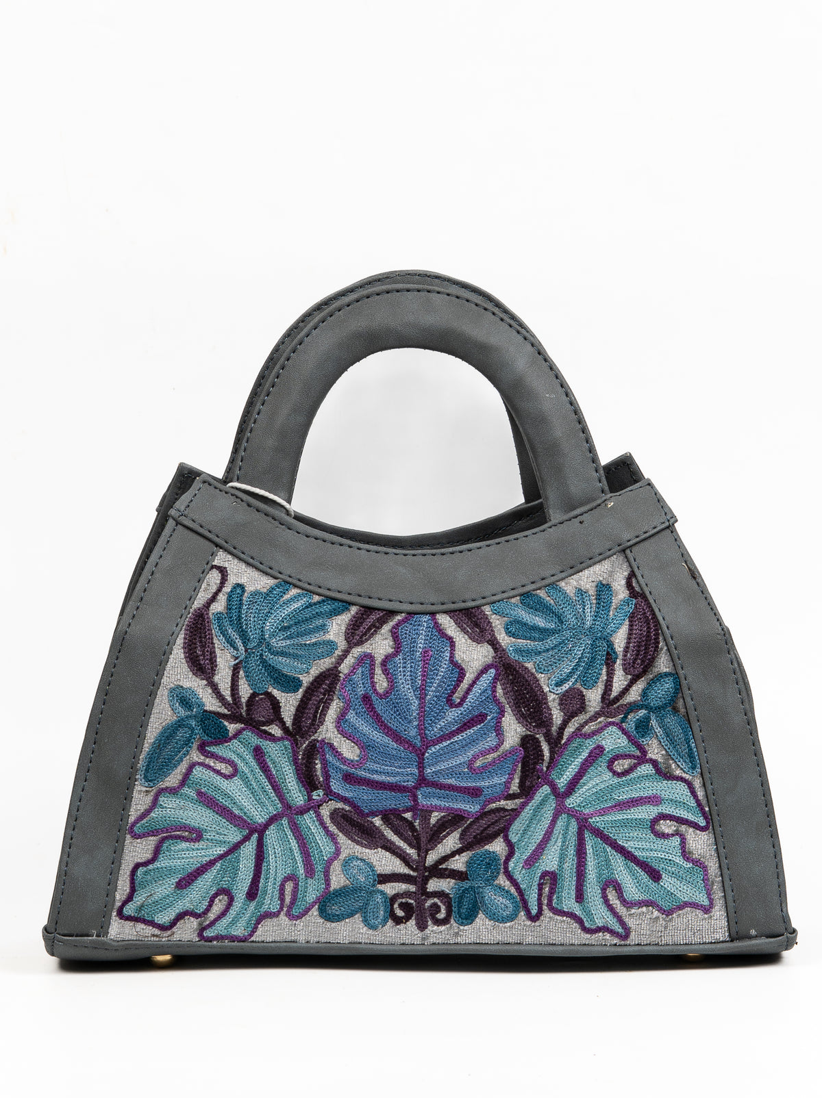 Straight-on view of the trapezoid-shaped grey handbag with symmetrical blue and teal foliage and a rounded handle.
