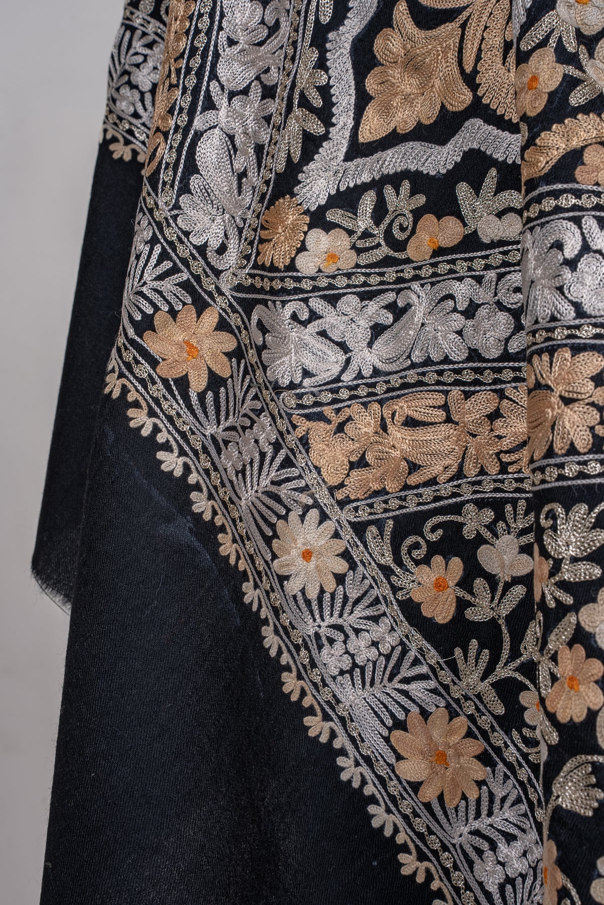 Lower draped detail of the black shawl, with ivory Aari floral bands and gold-toned flowers beside a plain black end