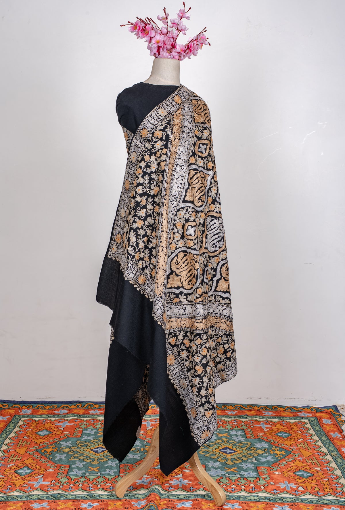 Full view of the black shawl on a mannequin, with ivory and gold-toned Aari medallions, floral borders and a plain end
