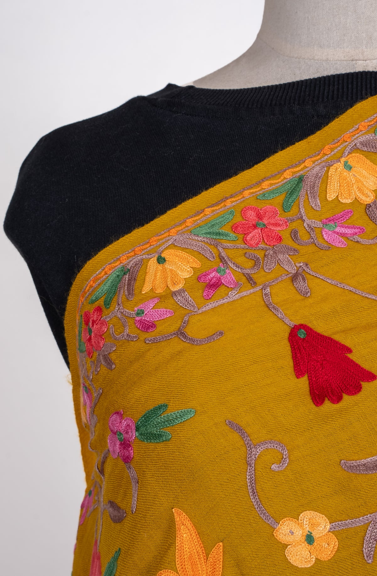 Shoulder detail of mustard shawl with colourful floral Aari embroidery and a narrow matching border