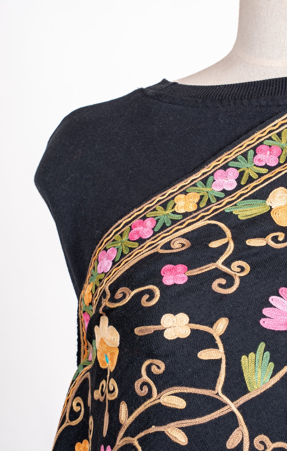 Close-up of the black shawl across a mannequin's chest, showing pink and cream flowers and a narrow Aari floral border.