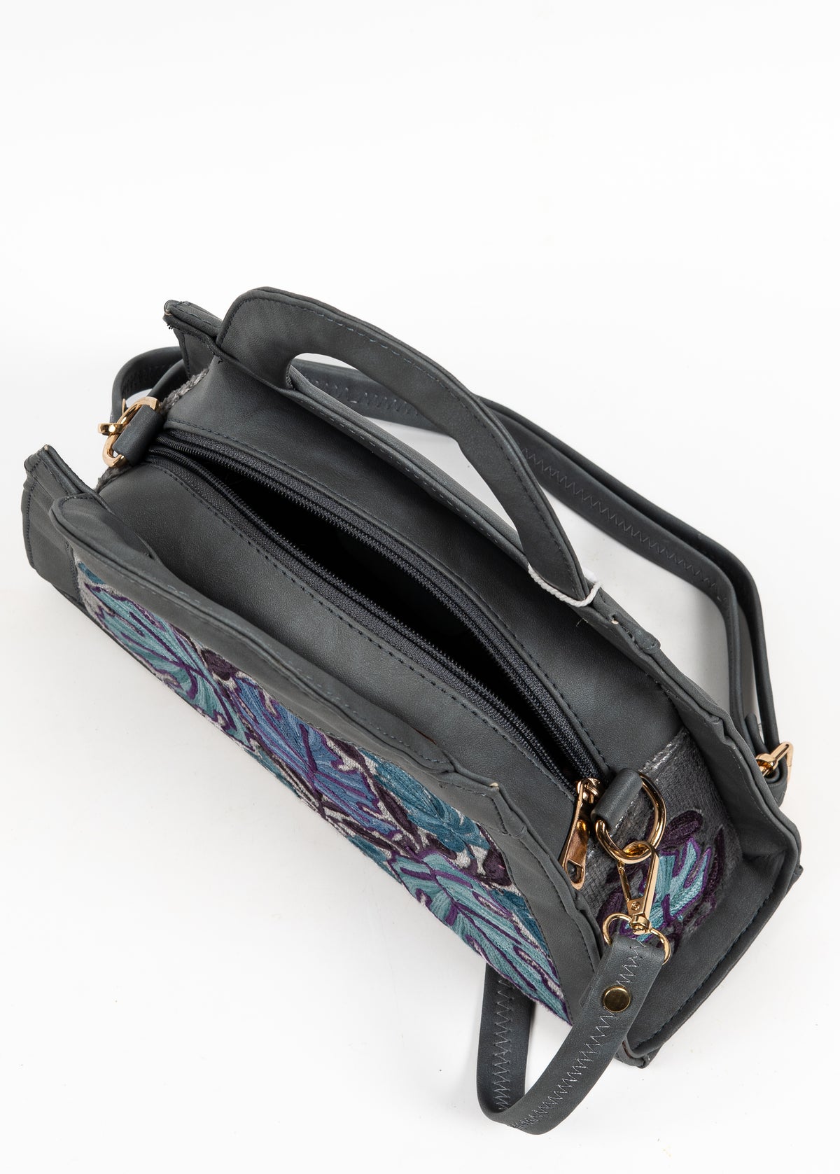 Top view of the grey handbag with its zipper open, revealing the dark interior between the folded handles.