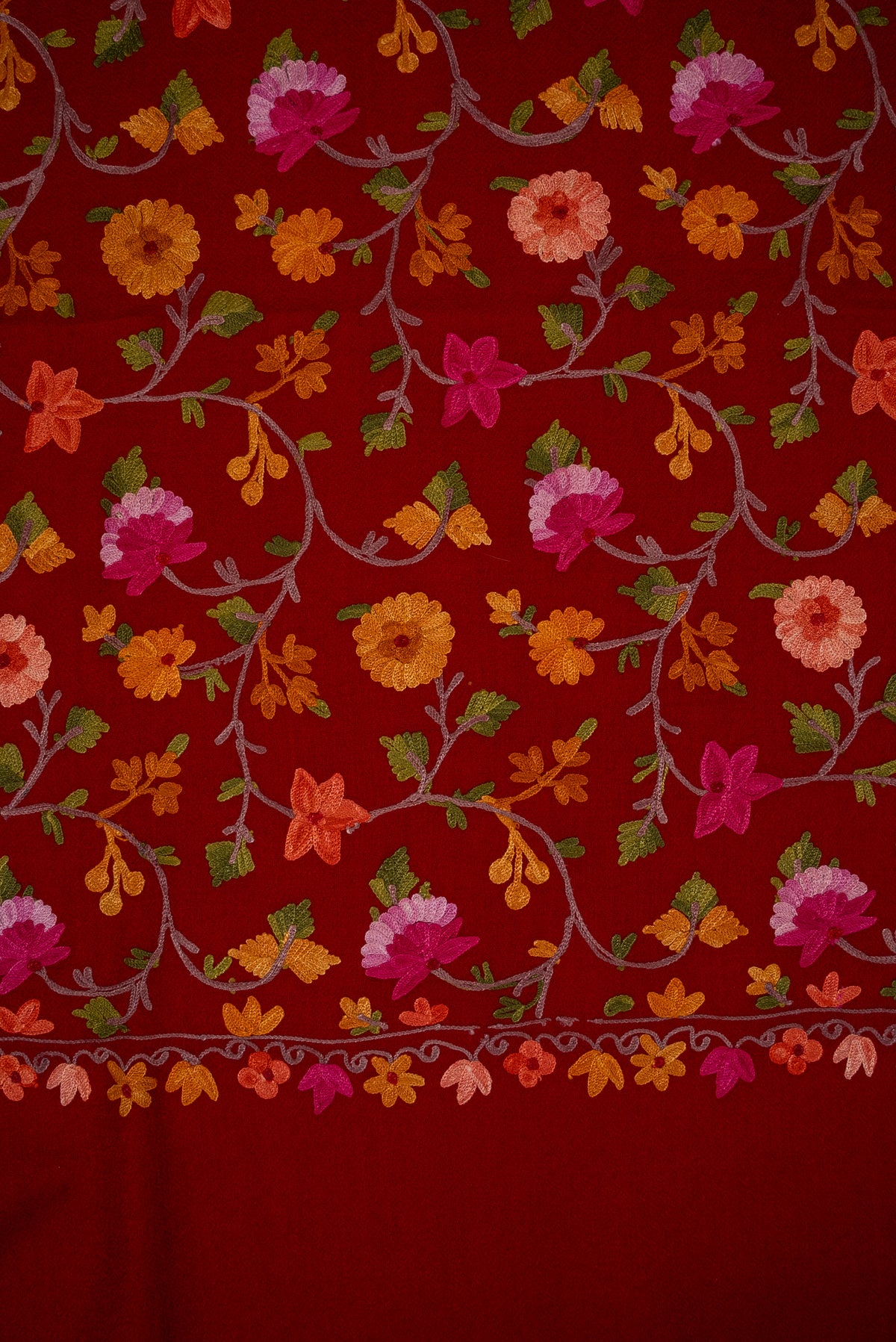 Close-up of the crimson shawl’s pink, orange and coral Aari flowers, green leaves and narrow lower floral border