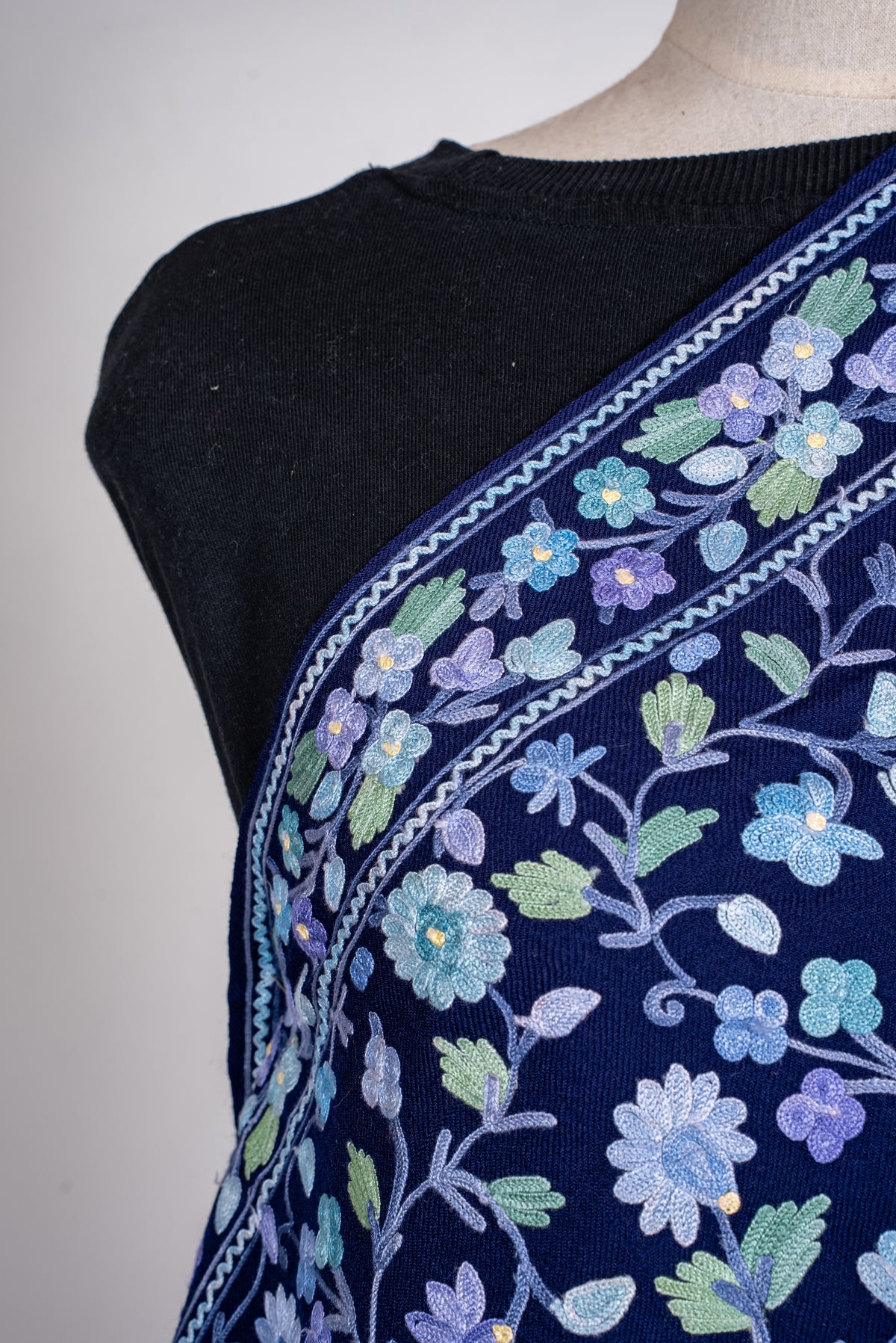 Shoulder close-up of the sapphire shawl, with blue and lavender Aari flowers, mint leaves and zigzag-edged borders