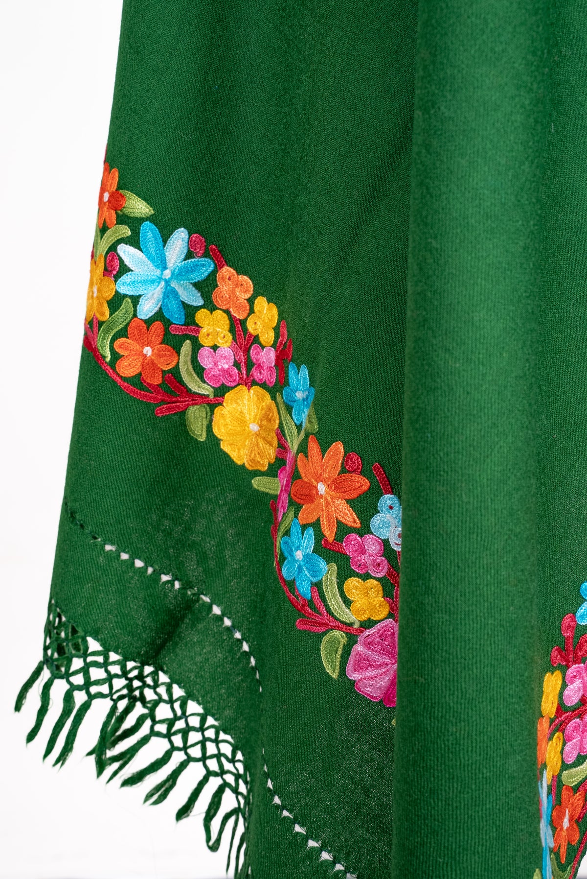 Lower draped detail of the forest-green shawl, with colourful Aari flowers above openwork and green knotted fringe