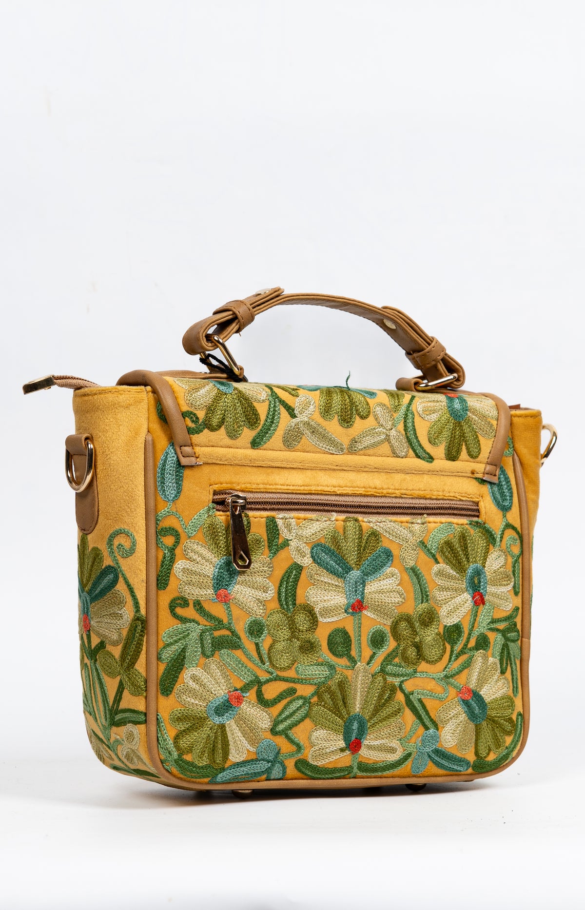 Angled back view of the mustard bag showing embroidered flowers, a horizontal zip pocket and a short top handle.
