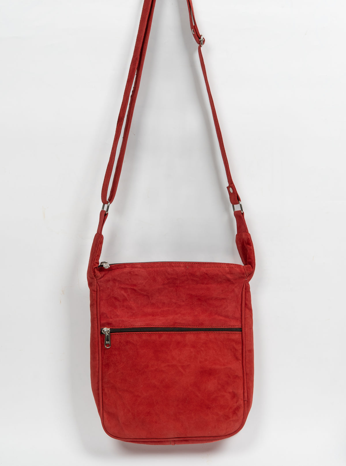 Back of the red crossbody bag with a plain panel, horizontal zip pocket and adjustable shoulder strap.