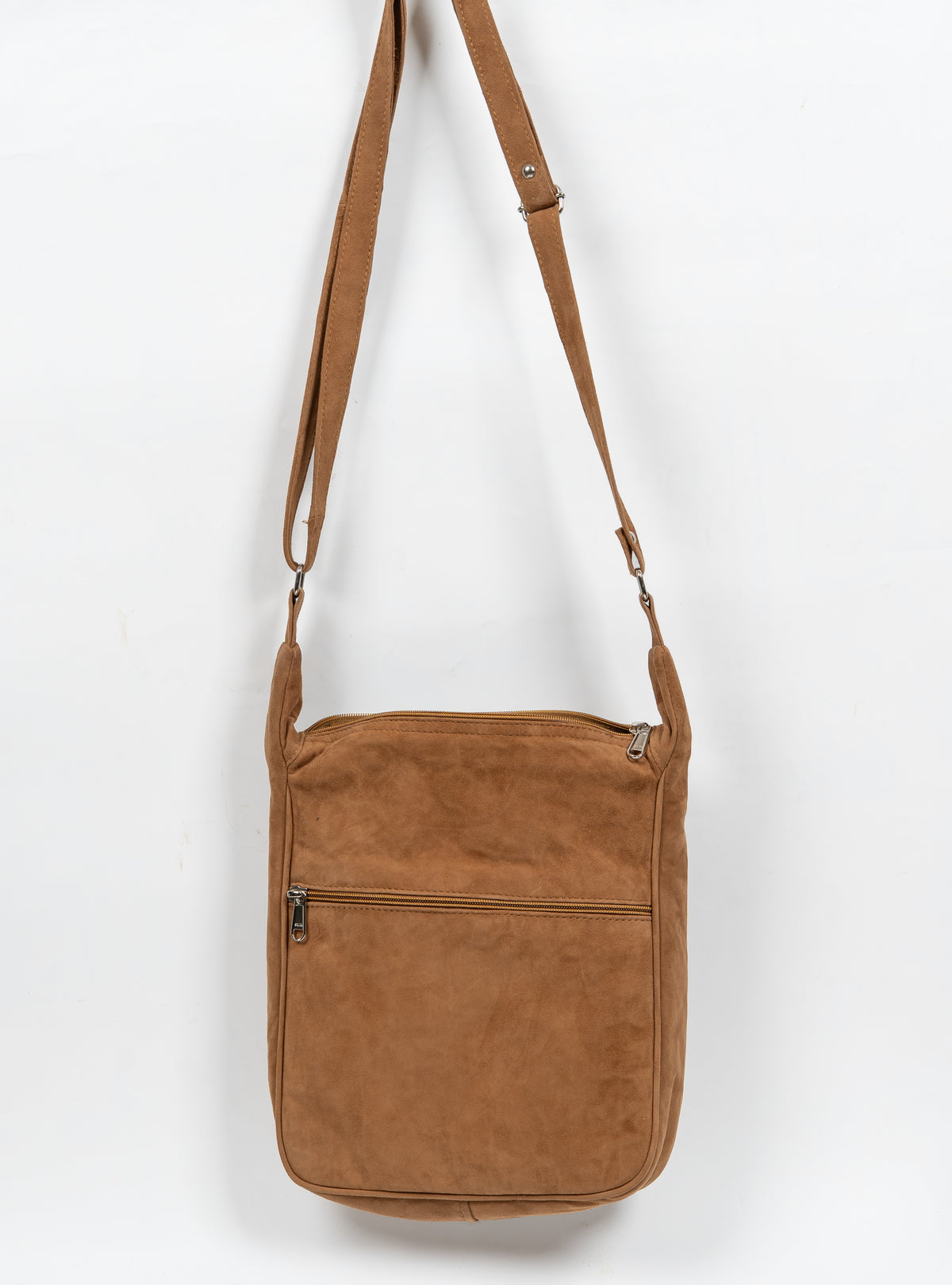 Plain brown back of the sling bag, with a horizontal zip pocket and long adjustable shoulder strap