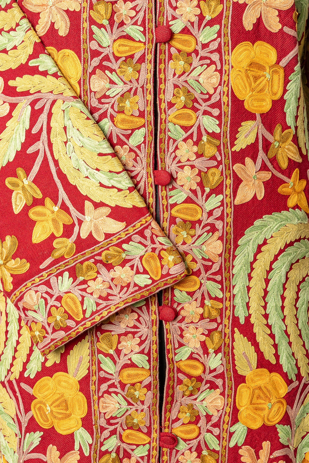 Detail of the maroon jacket's embroidered cuff and floral front border with matching covered buttons