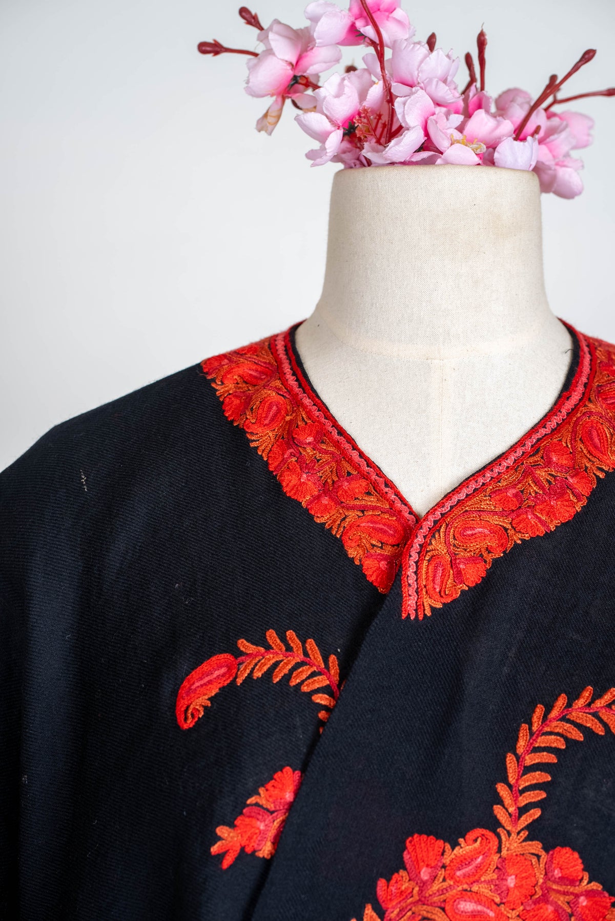 Close-up of the black cape's neckline, edged with red and orange leaf and paisley embroidery
