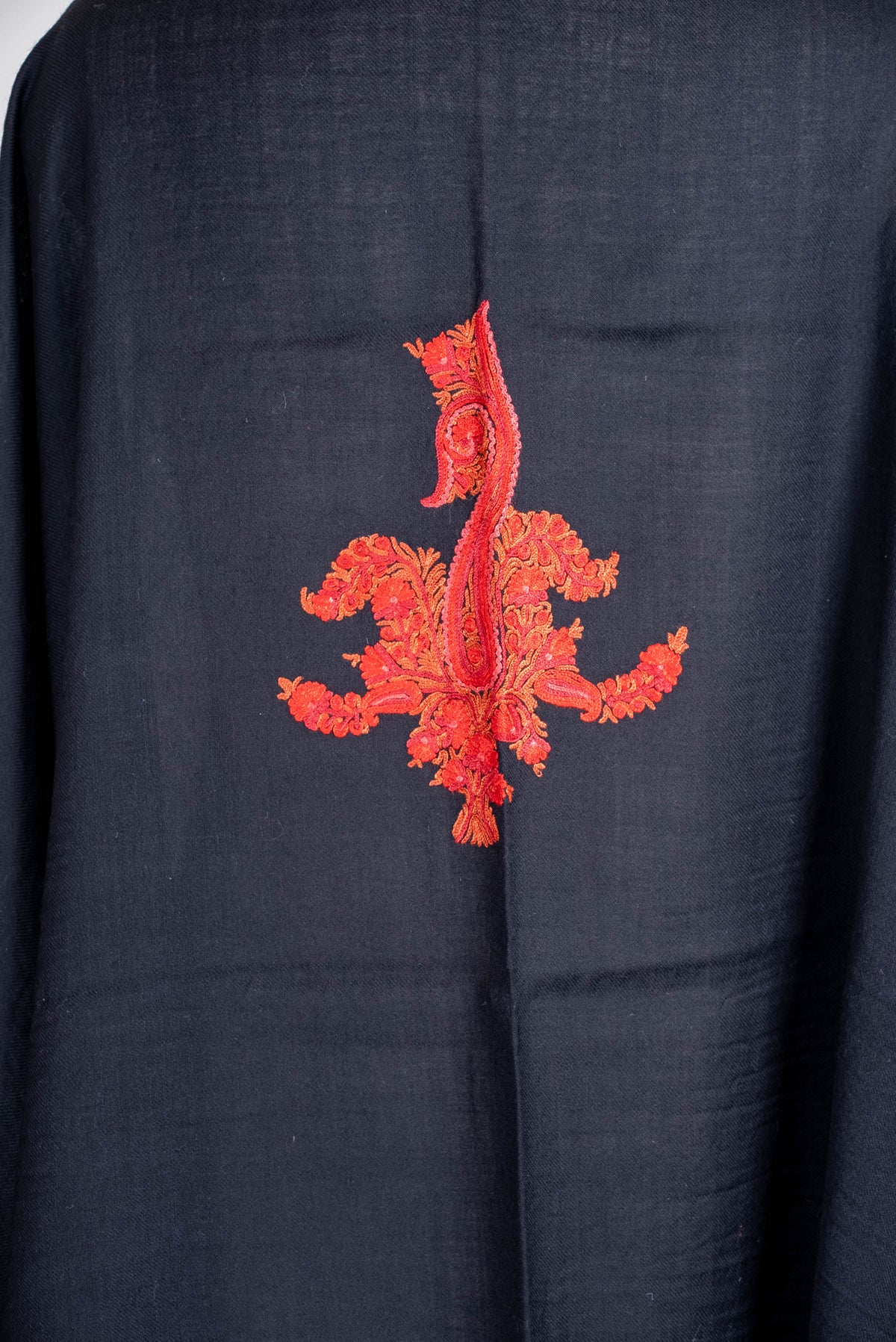 Close-up of the cape's red-orange embroidered back motif, with an elongated paisley and curved floral branches