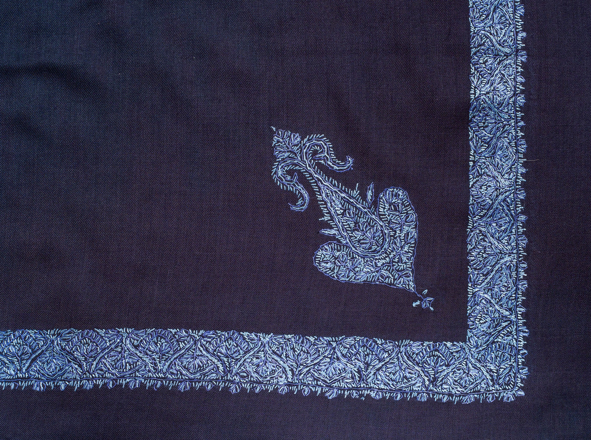Flat corner of the dark navy rumal showing an icy blue ornamental motif beside the dense floral border