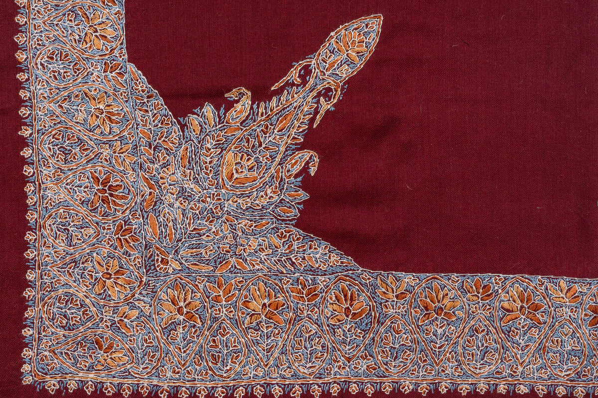 Crimson rumal corner laid flat with a broad multicoloured Sozni border extending inward into a pointed paisley motif