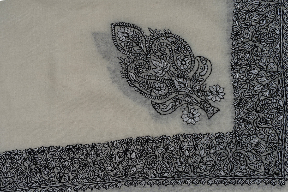 Close-up of a black Sozni corner motif with paired paisleys and flowers beside an ivory rumal border