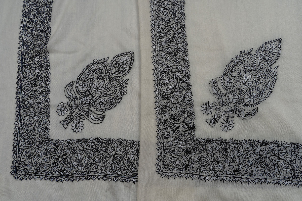 Overlapping ivory rumal corners showing both sides of black Sozni floral motif and border stitching