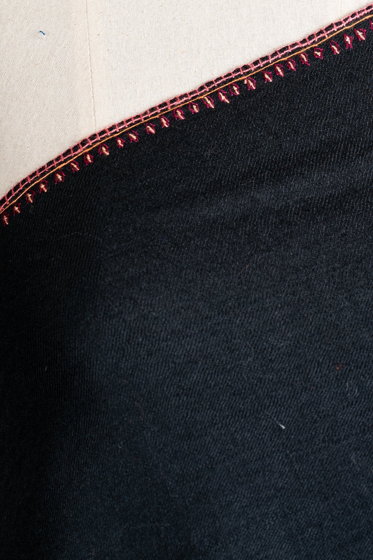 Close-up of the black shawl shoulder edge showing red stitching and tiny leaf-like embroidered details.