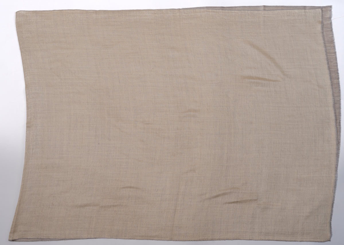 Light beige side of a reversible Merino wool stole laid flat, with narrow darker edges visible along the rectangle