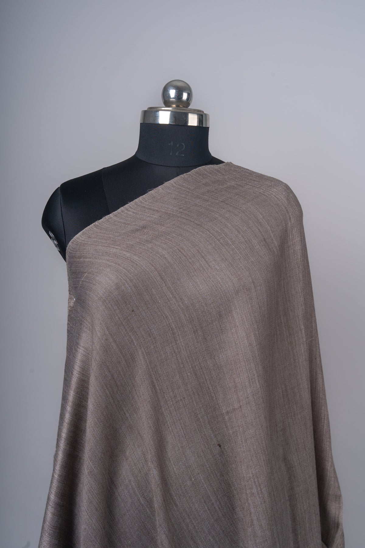 Closer view of the mocha stole across a mannequin shoulder, showing the fine subtly streaked weave.