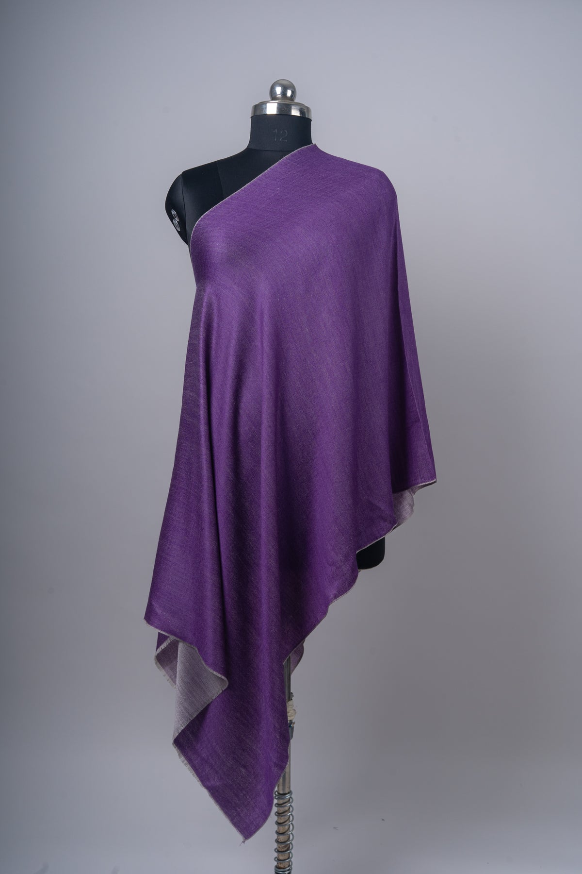 Purple stole falling in long folds from one shoulder of a mannequin, with the ash grey reverse turned out at the lower edge