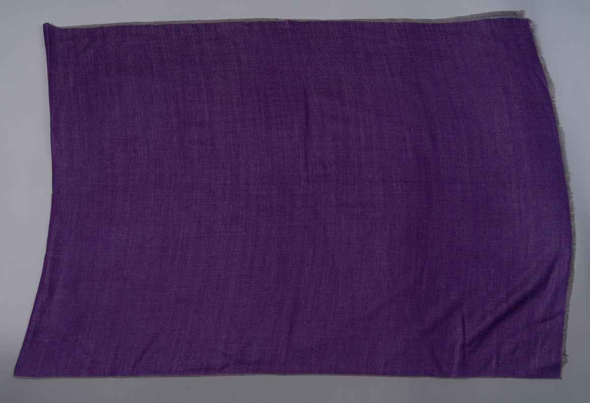 Purple side of a rectangular reversible Merino wool stole laid flat, with a narrow grey edge visible along the top
