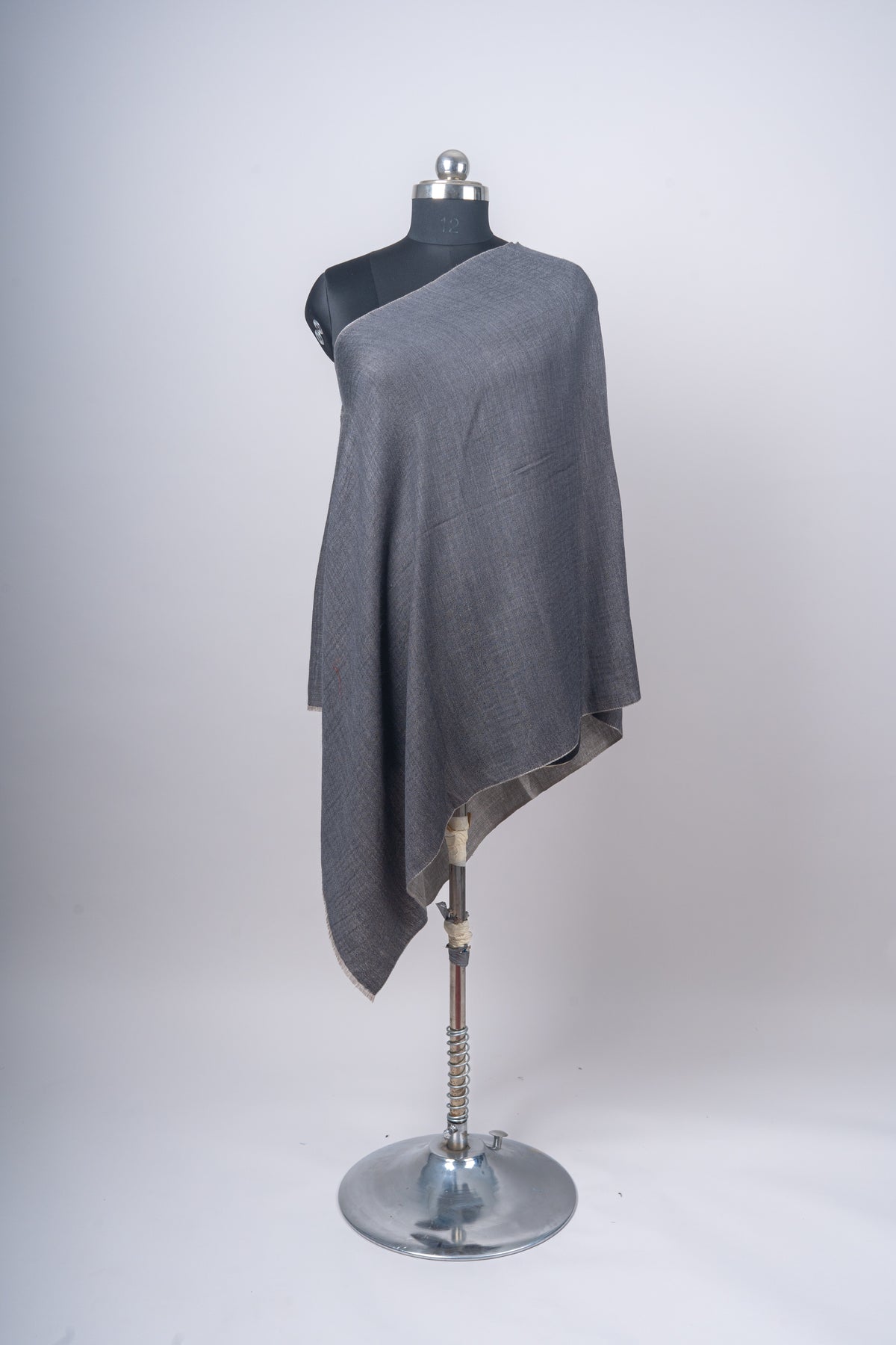 Plain charcoal stole draped diagonally across a mannequin, with one long pointed end and a pale reverse fold.