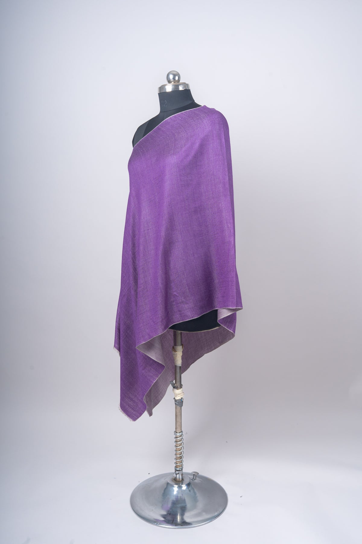 Side-angled view of a purple Merino wool stole on a mannequin, with a grey reverse showing below the draped edge