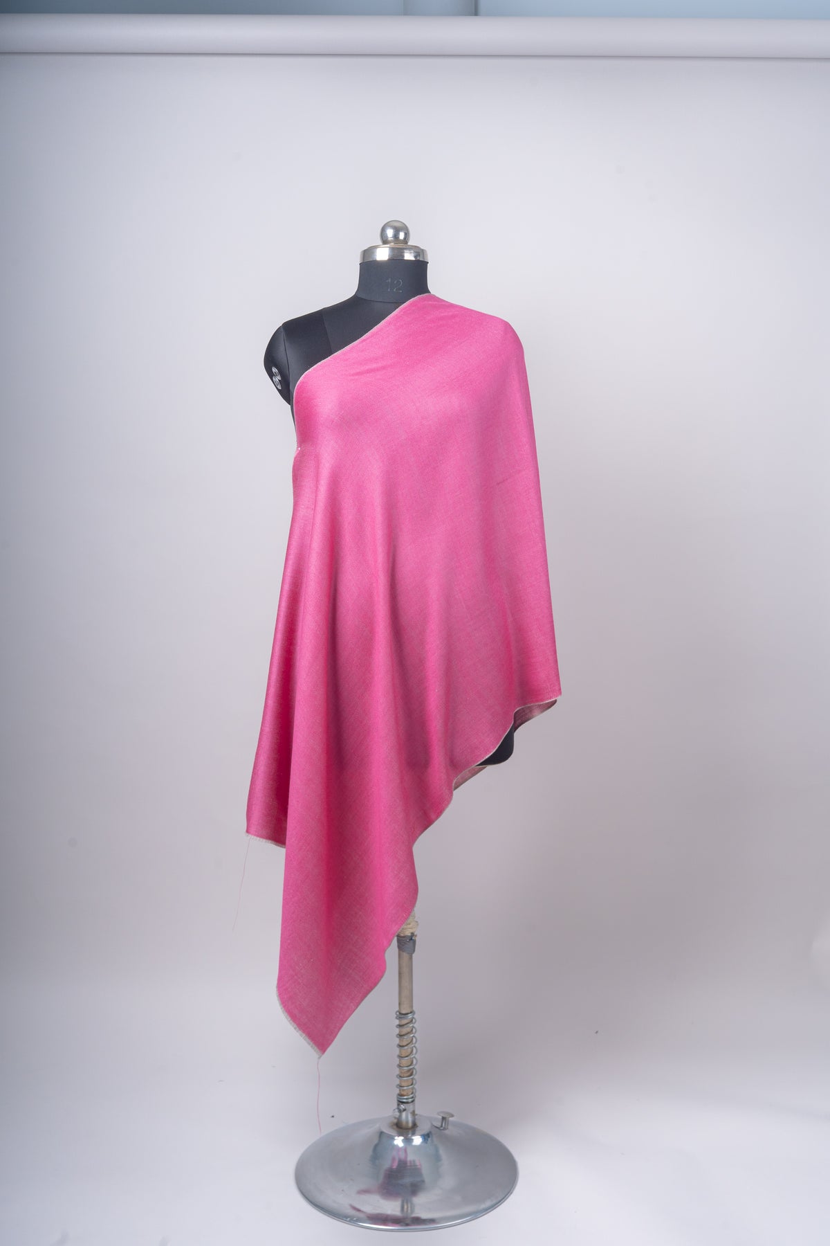 Full-length front view of the plain pink stole draped diagonally over a black mannequin