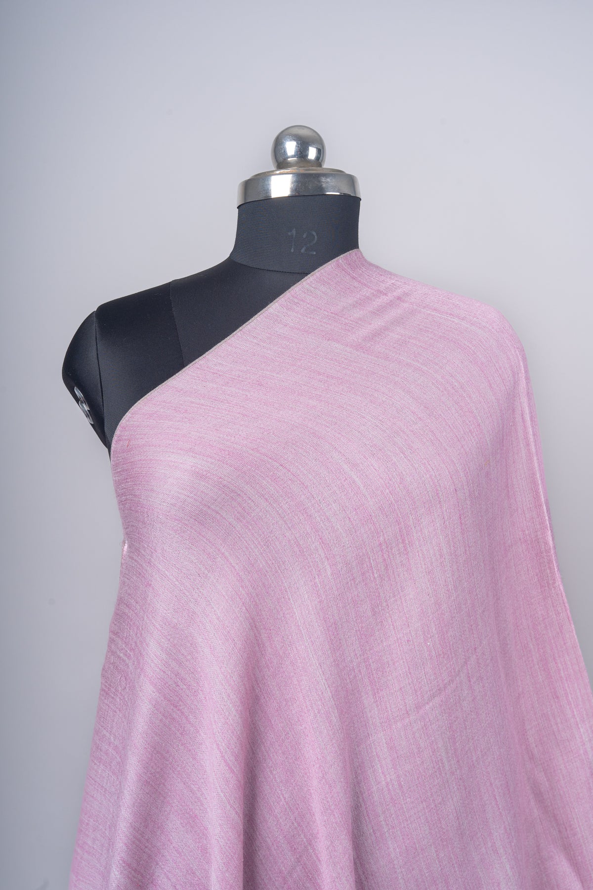 Close-up of a rose-pink stole over one shoulder of a black mannequin, showing the fine plain weave and gentle sheen