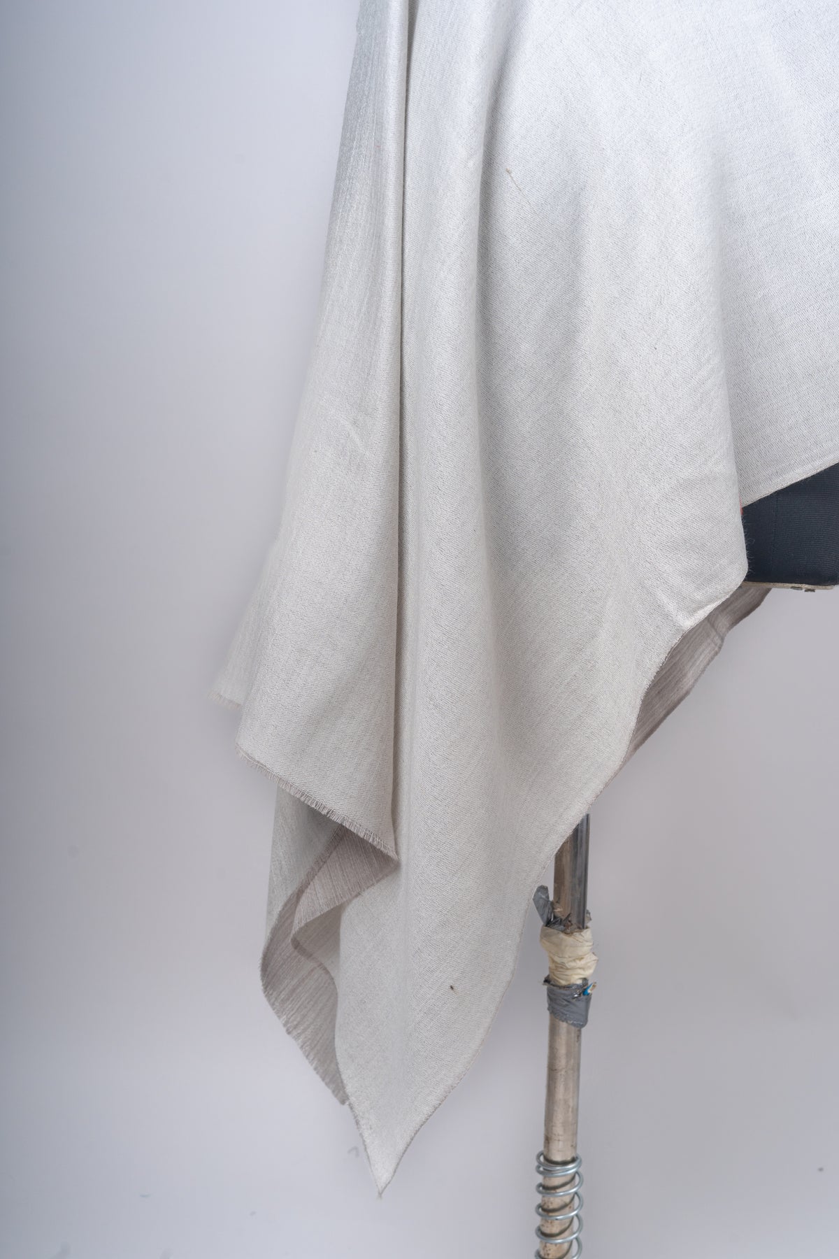 Detail of the ivory stole’s hanging folds and fine edge, with the taupe reverse peeking underneath