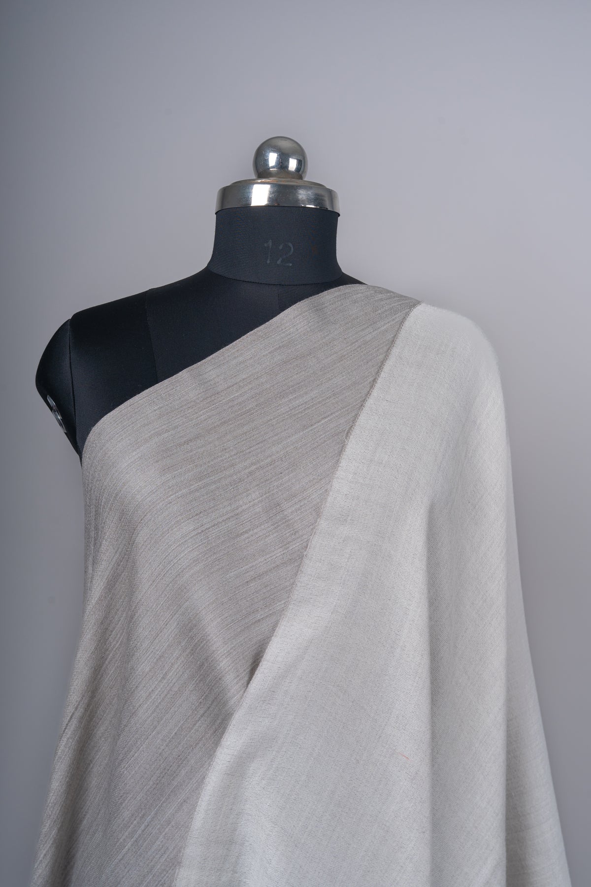 Close view of the reversible Merino wool stole showing taupe across the chest and an ivory fold over one shoulder