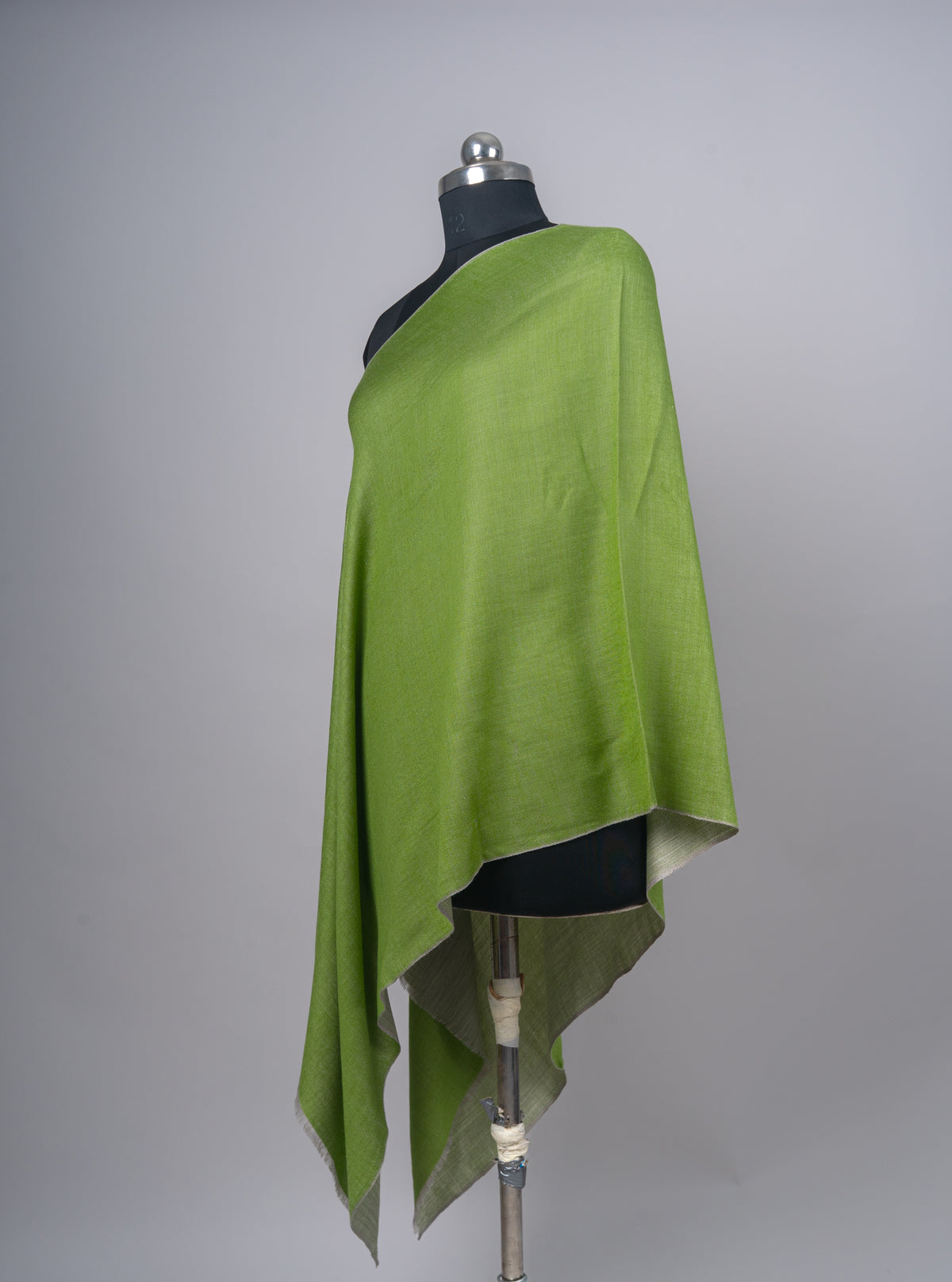 Side-angled green reversible stole on a mannequin, with its mist-grey underside showing below the draped edge