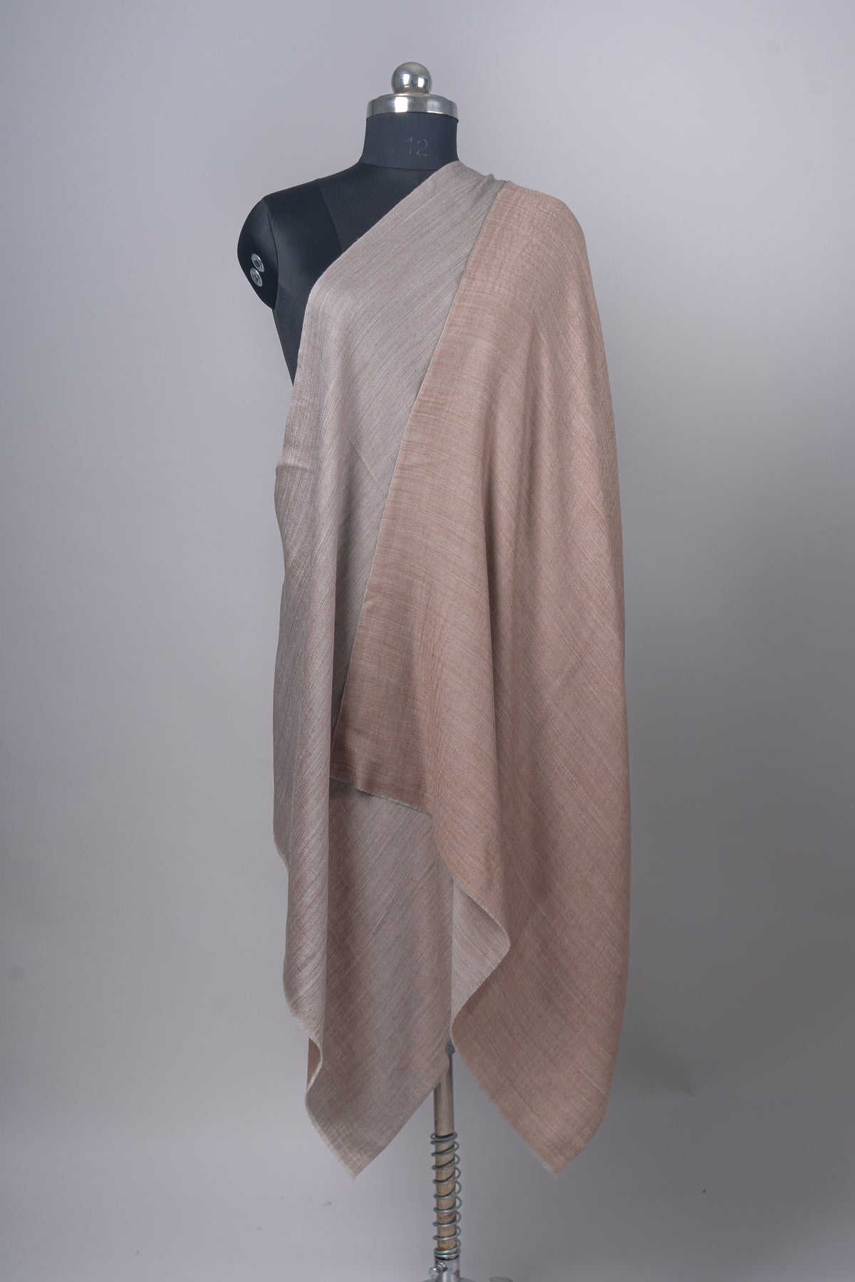 Reversible stole arranged on a mannequin to show the almond-beige and ash-grey faces side by side.