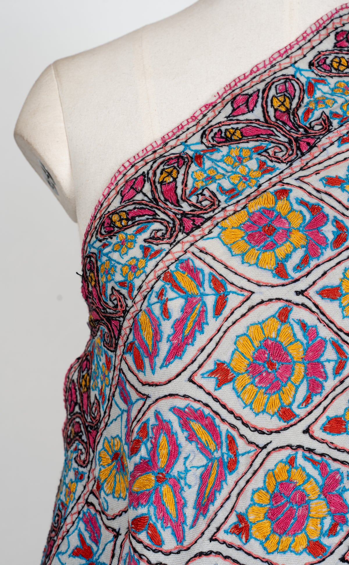 Shoulder detail of an ivory stole with colourful Sozni floral medallions and a pink, blue and yellow paisley border