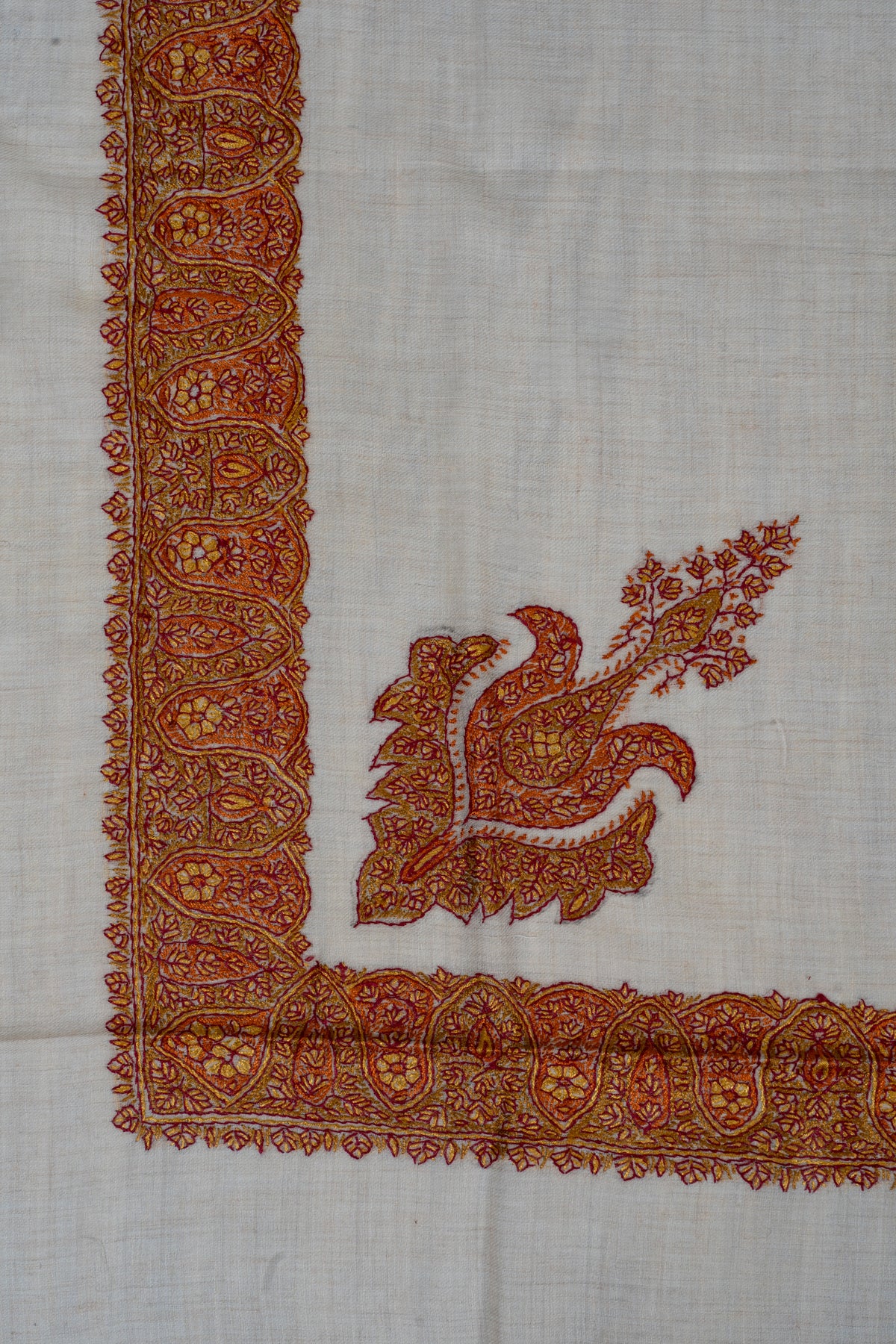 Ivory rumal corner with a saffron and maroon floral motif beside a gold-toned border of repeating paisleys