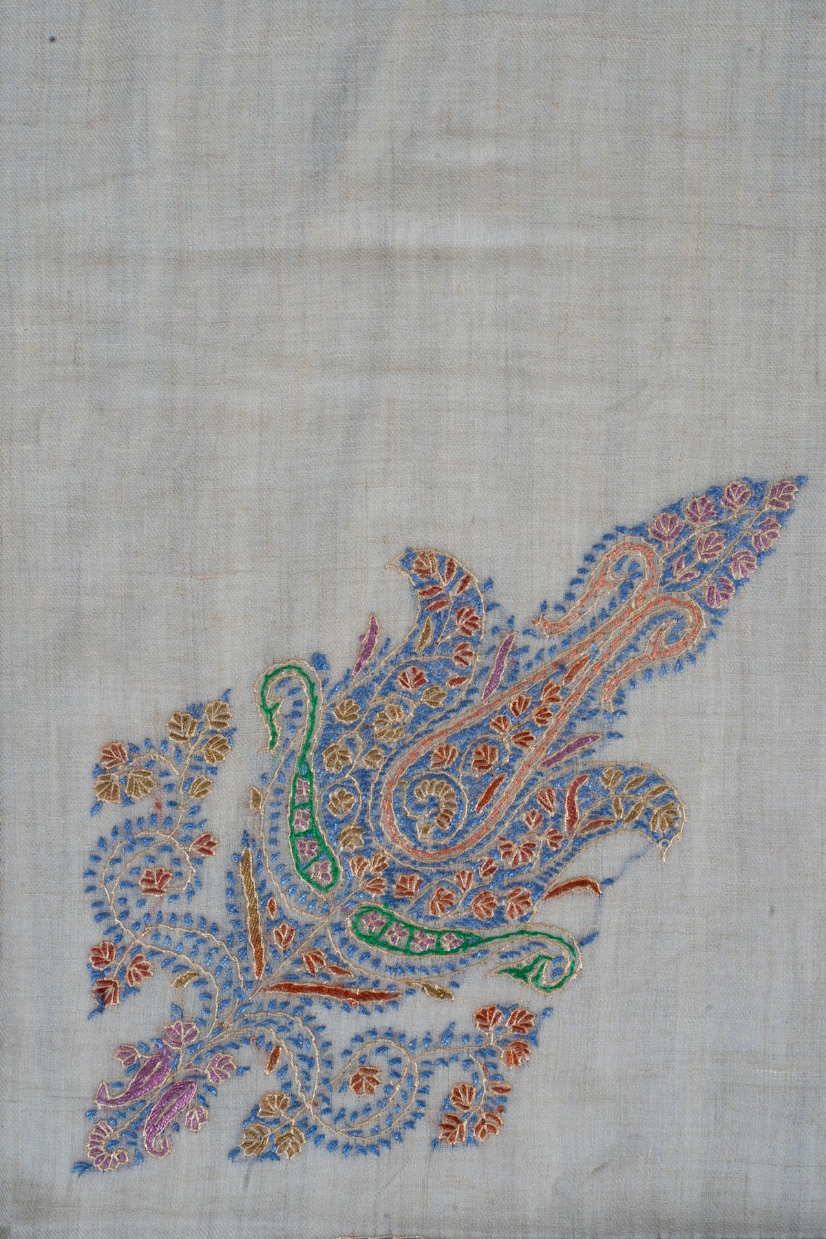 Close-up of a Sozni paisley with blue, green, pink and orange floral details on cream cashmere.
