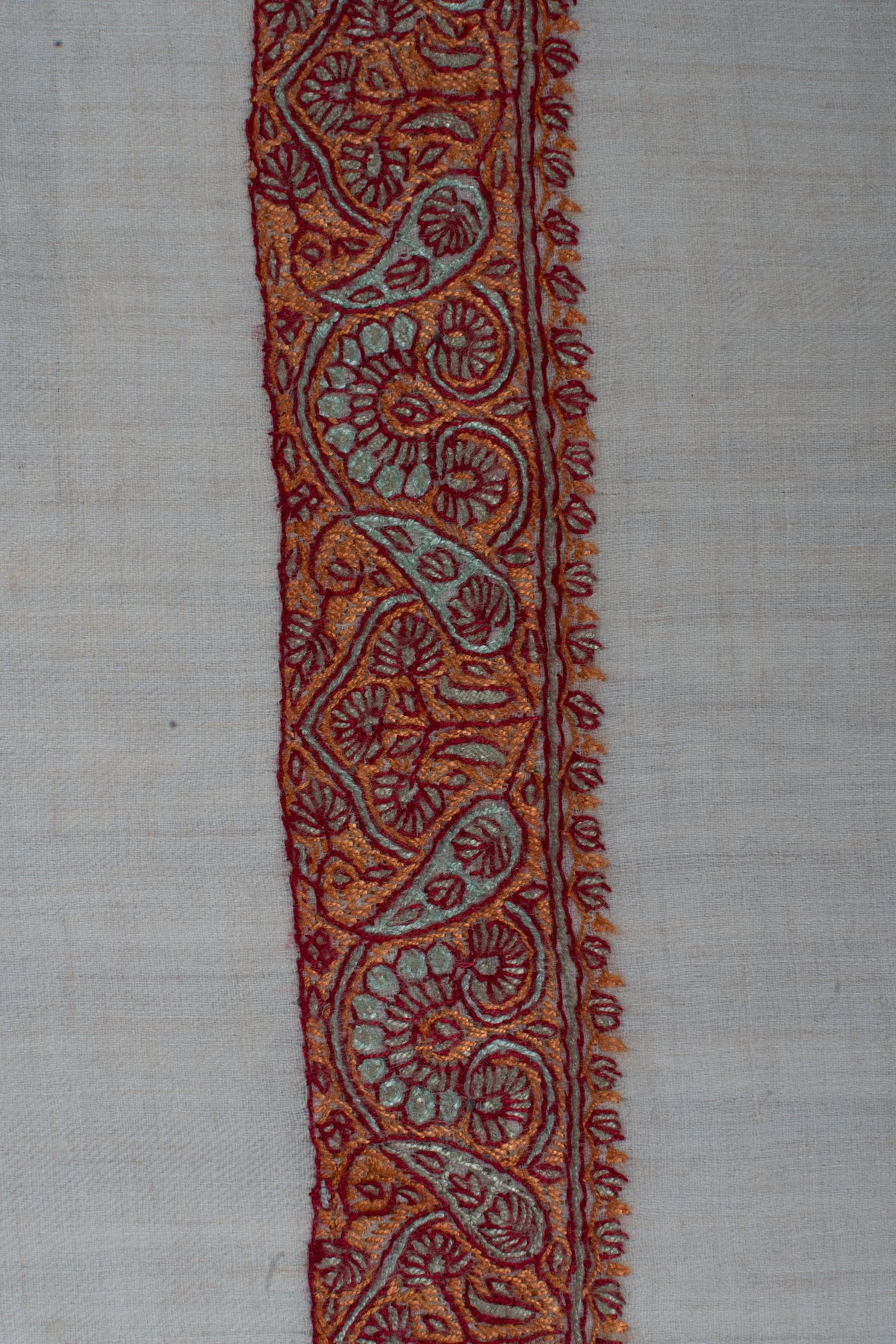 Close-up of a copper and sage Sozni rumal border with curling paisleys, small flowers and dark red outlines