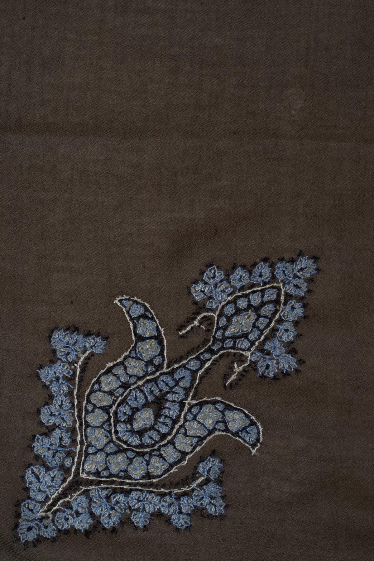 Close-up of the pale blue and silver-toned floral motif embroidered on mocha cashmere