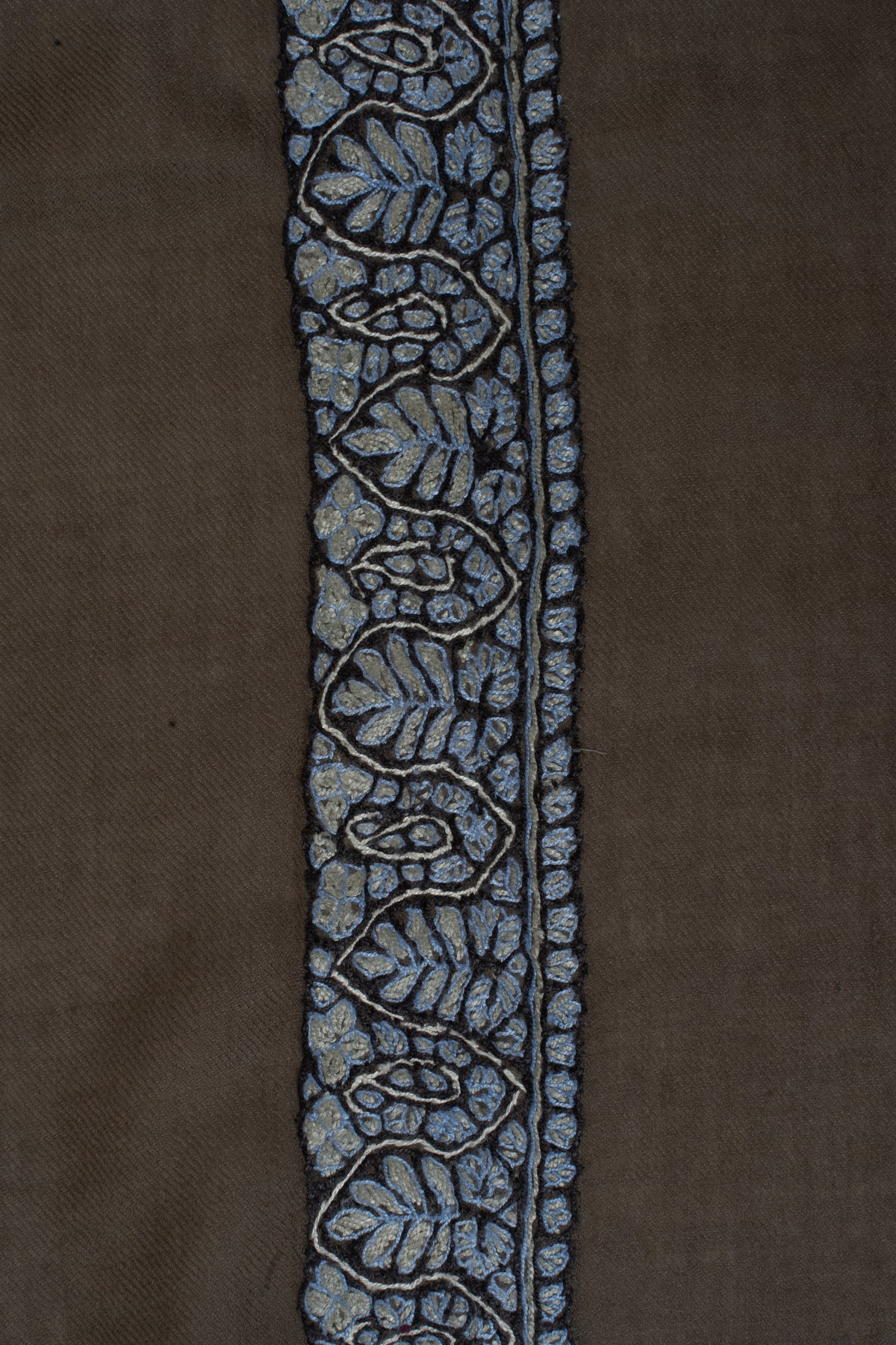 Close-up of pale blue leaves and curled floral forms in the mocha rumal's embroidered border