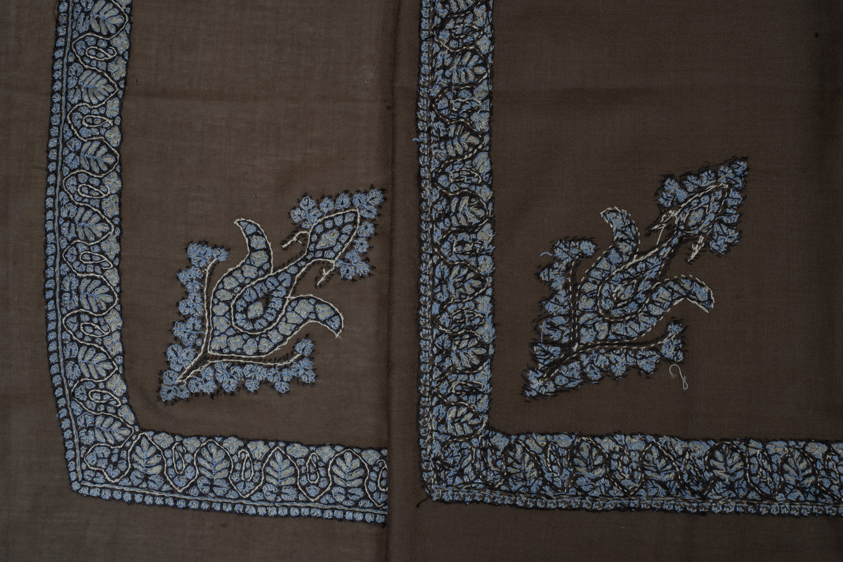 Overlapping mocha rumal corners showing the front and reverse of pale blue embroidery