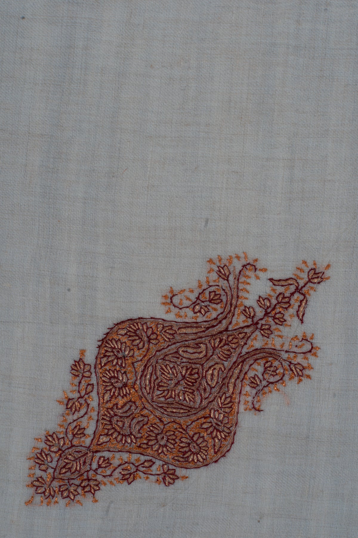 Close-up of the copper-rust floral motif with curling tips and small flowers on cream cashmere