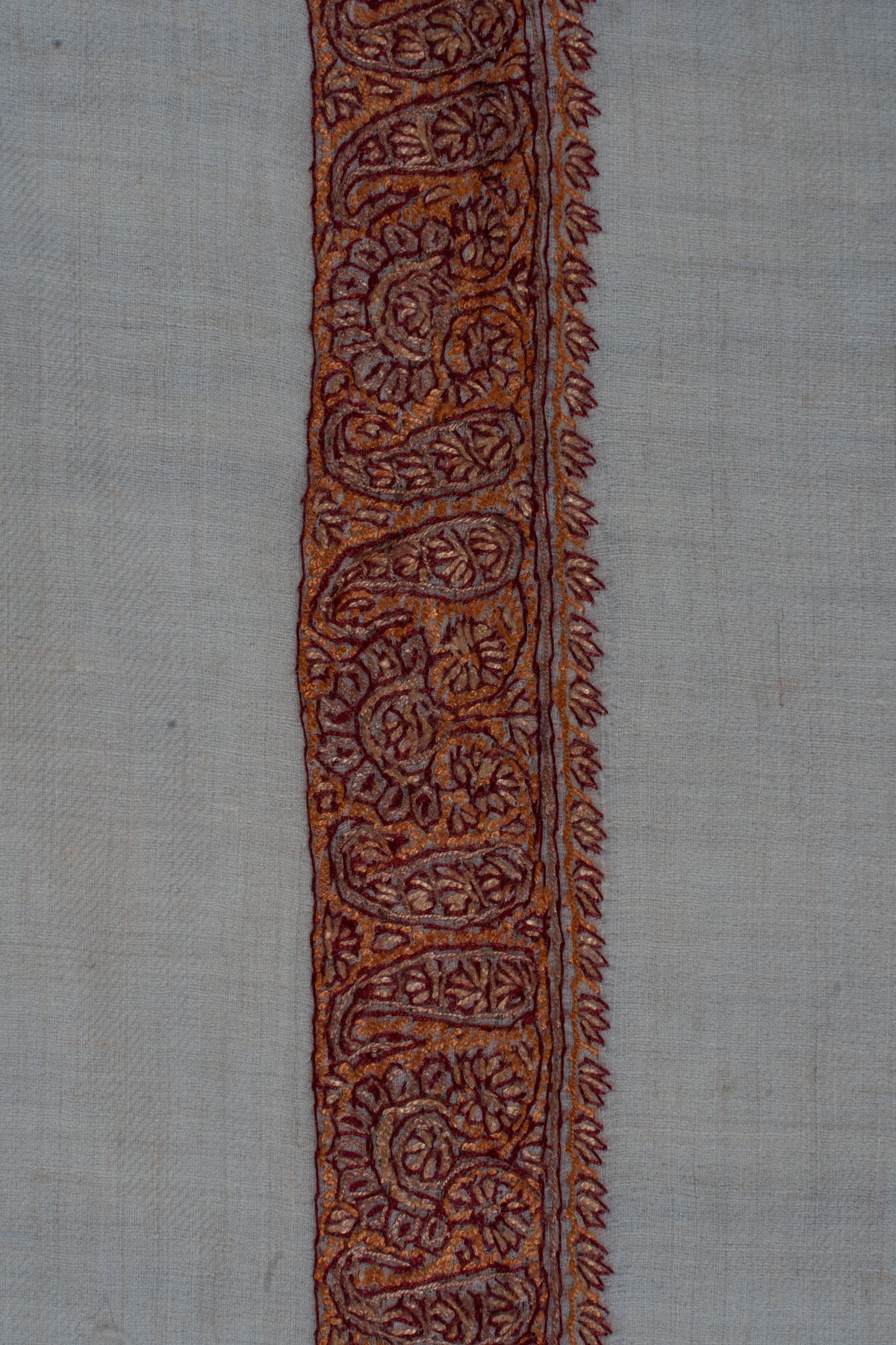 Close-up of repeating paisleys and fine leaf edging in the rumal's copper-rust border
