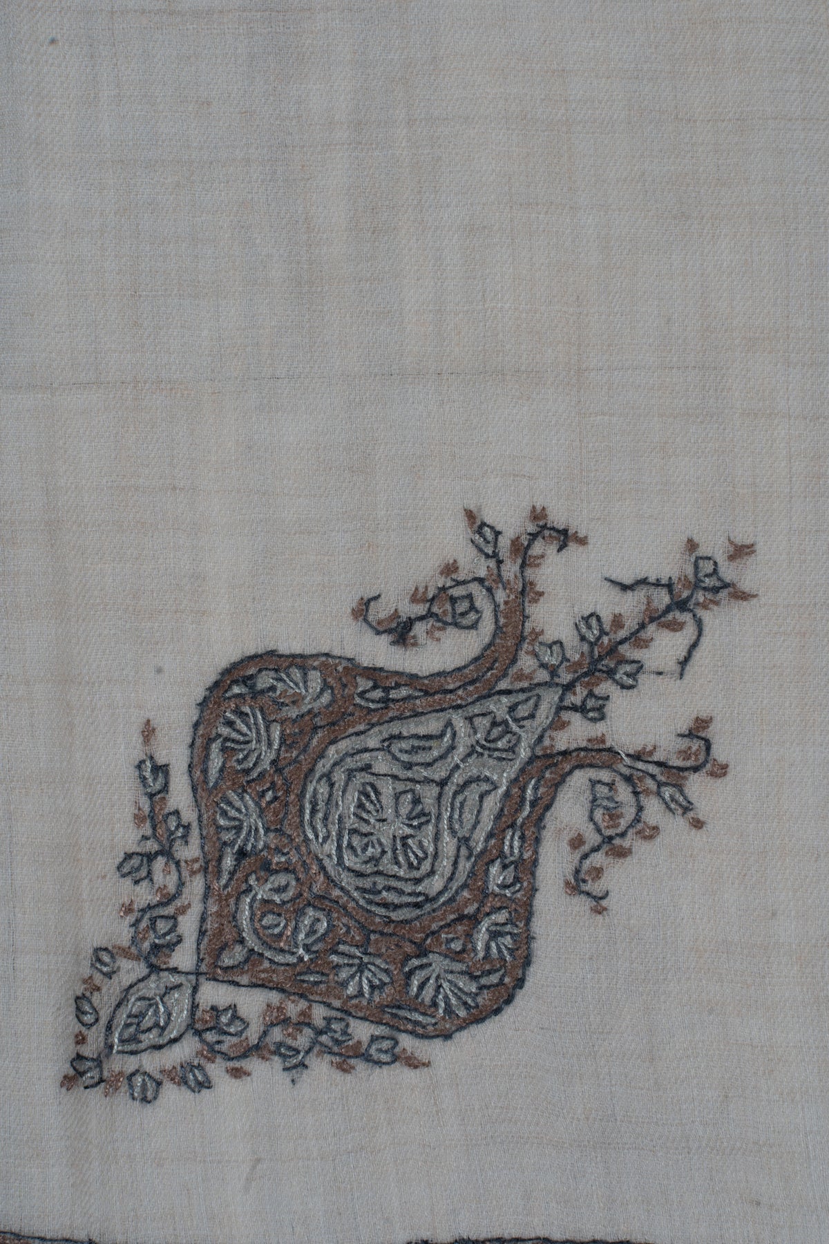 Close-up of the rumal's grey-blue floral motif with curled tips and small trailing leaves