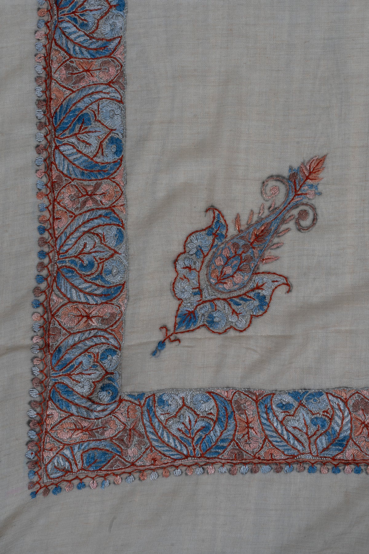Beige rumal corner with a small coral and powder-blue Sozni paisley inside a broad leaf-patterned border