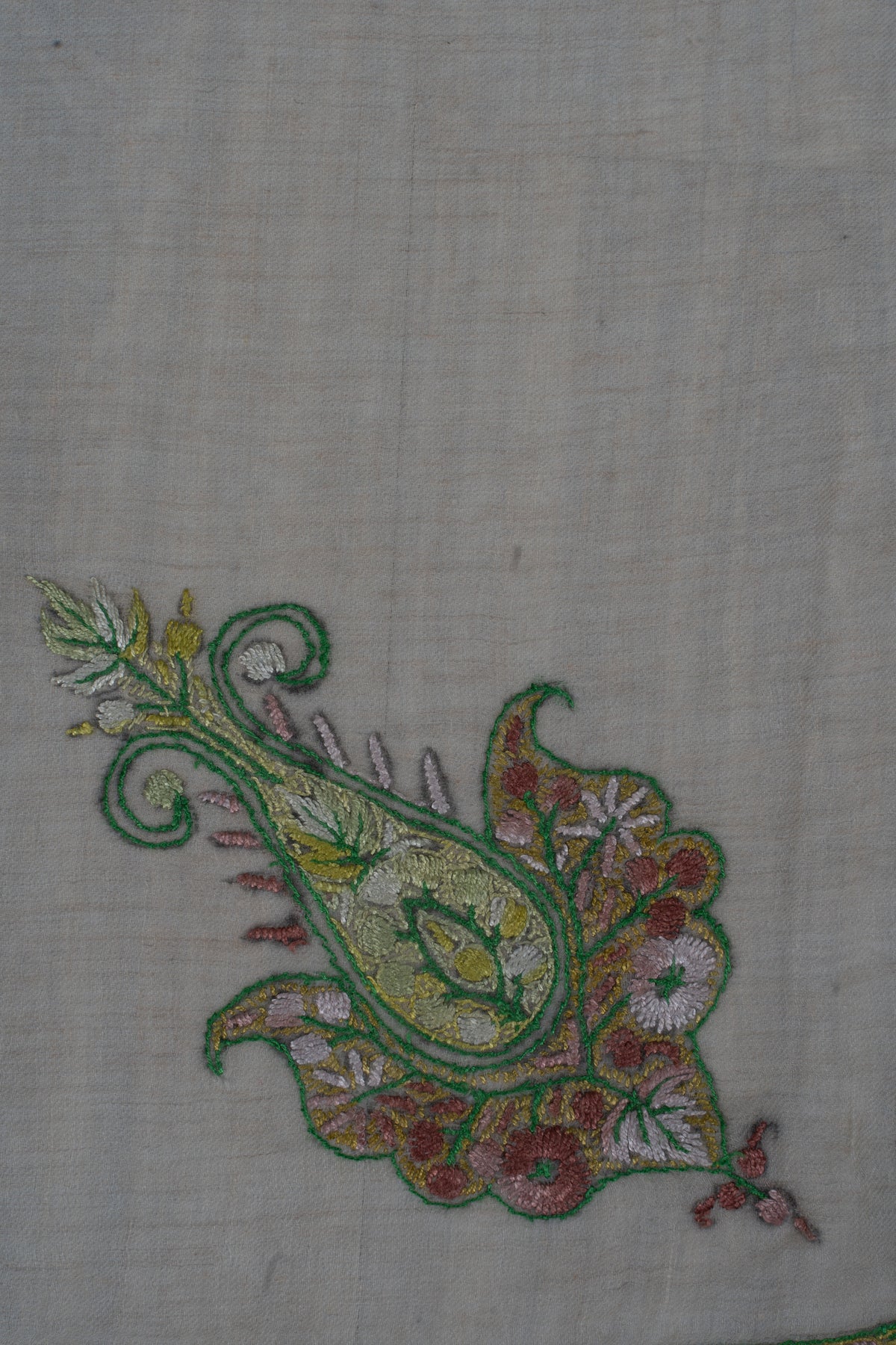 Close-up of a green-outlined Sozni motif with a teardrop centre, rose flowers and pale gold details on beige fabric