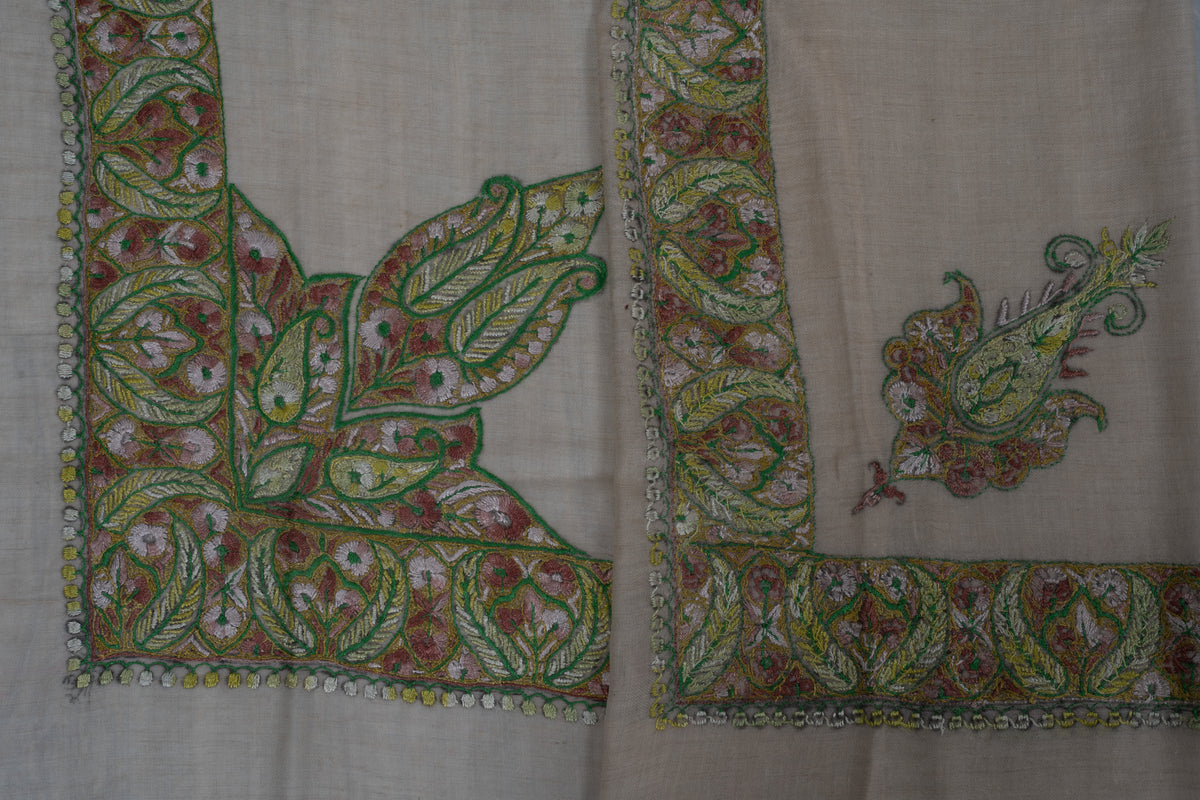 Overlapping pale beige rumal corners showing green and rose Sozni borders and two differently shaped corner motifs