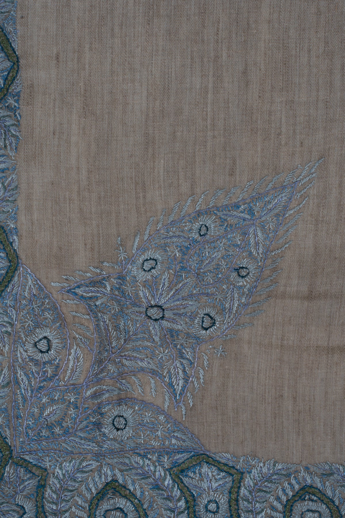 Close-up of pale blue leaves and rounded flower forms in the rumal's large corner design